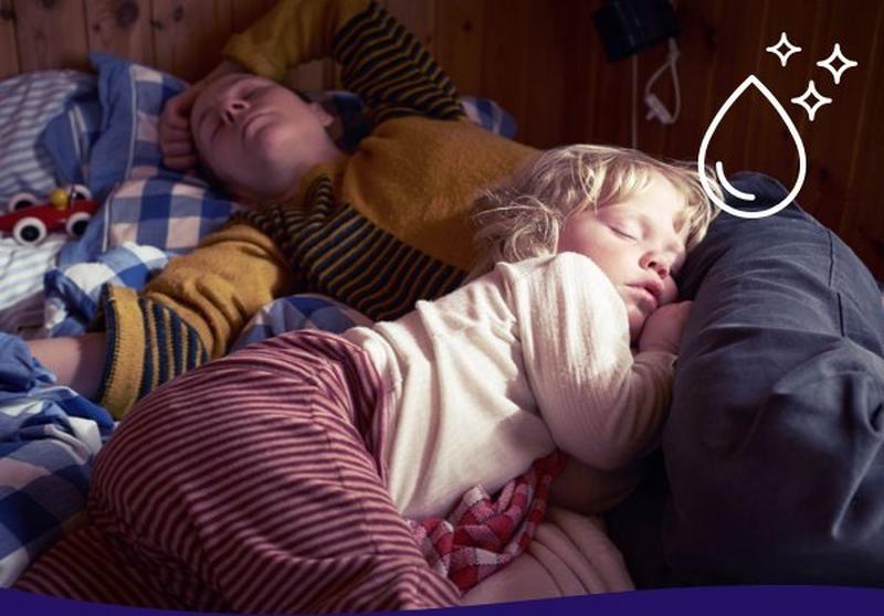 A mother and daughter snuggled up asleep in bed