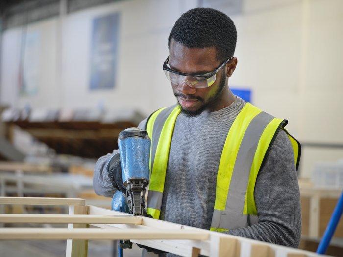 Male employee at the Dreams bed factory constructing a divan bed base