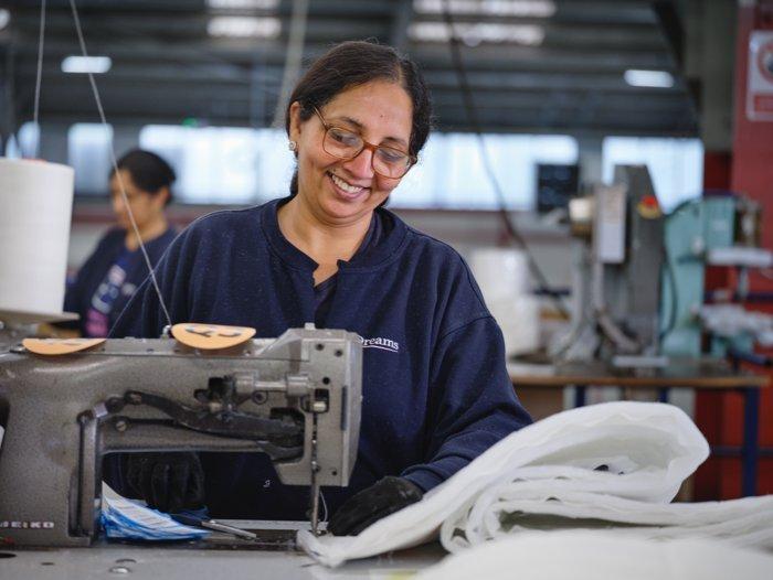 Seamstress at the Dreams bed factory stitching the side panelling for a mattress