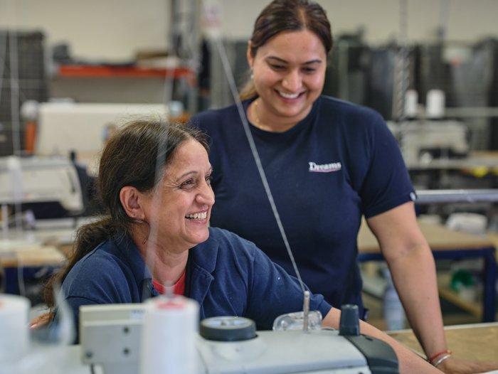 Two employees at the Dreams bed factory smiling whilst working