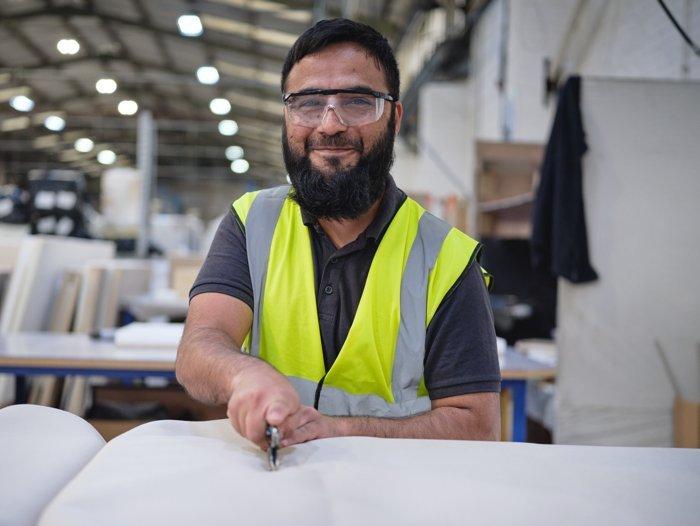 An employee at the Dreams bed factory cutting fabric for mattresses