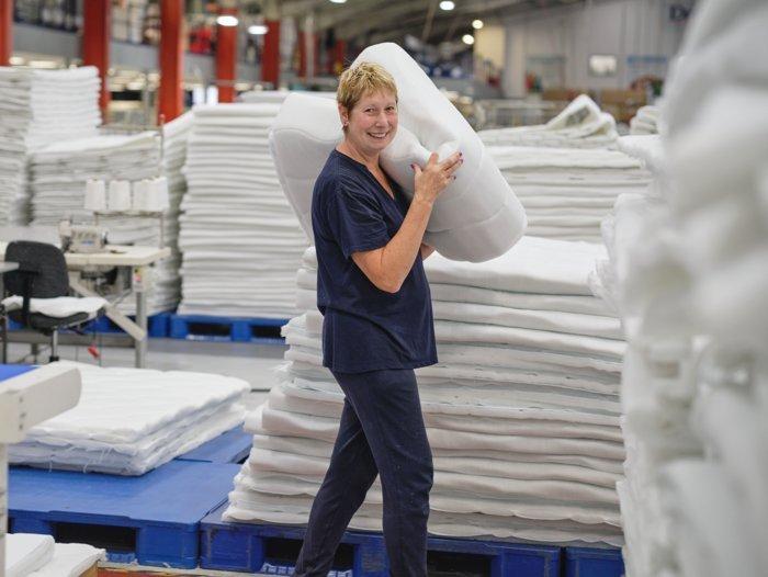 A lady working at the Dreams bed factory moving mattress fabric to her station 