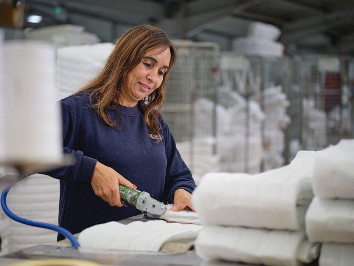 Female employee at the Dreams bed factory working on a mattress border
