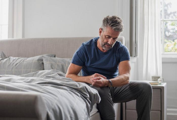 man sat on edge of bed checking bed height compared to his own