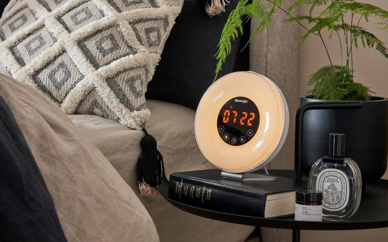 a round clock on a book on a bedside table