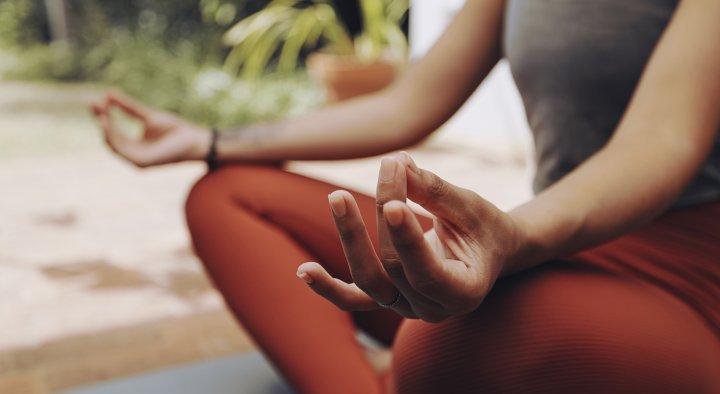 body shot of a woman sat in a medative pose with hands on her knees