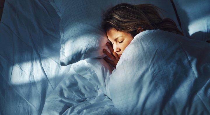 woman sleeping snug with light coming onto the bed lighting her face