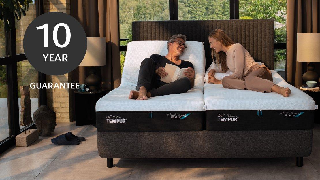 10 year guarantee | two people smiling, facing each other on a TEMPUR mattress, set in a bedroom