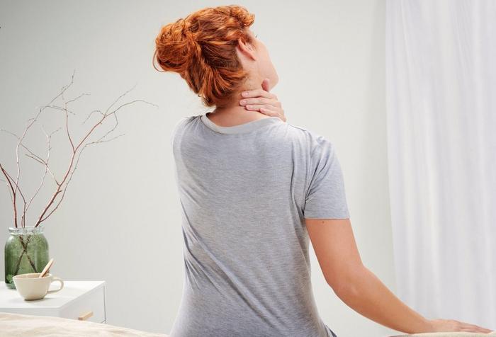 woman seen from behind rubbing her neck in pain