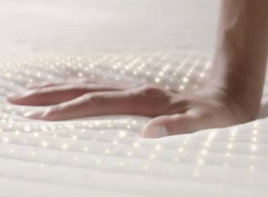 Hand pressing down on a mattress